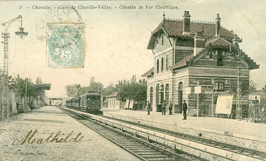 Intérieur de la gare avec un train électrique vers Paris à l’approche. 