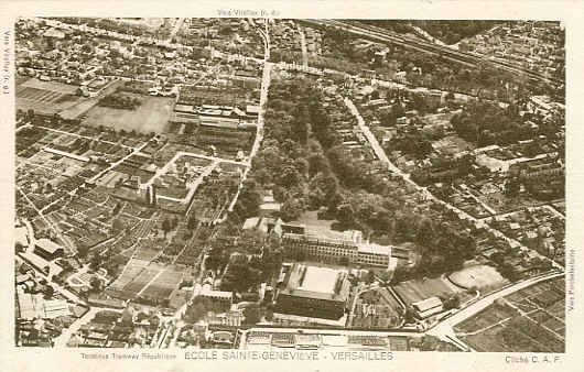 Dans les années 30, la rue d’Ecole des Postes  borde le parc de l’Ecole Sainte Geneviève sur la gauche, jusqu’à la route nationale. On reconnait sur gauche du cliché la mosaïque des cultures du pépiniériste Moser. Cliquer sur la vue pour l’agrandir